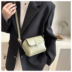 Detail view of a mint green crossbody bag featuring a matte finish and gold hardware