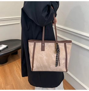 Detail einer großen beigen Tote-Bag mit dunkelbraunen Lederriemen und Tennis-Anhänger