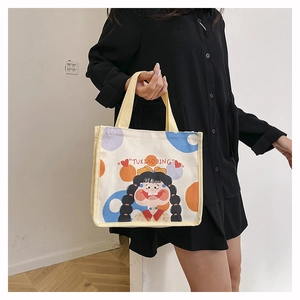 Detail of canvas tote bag featuring cute cartoon girl illustration and yellow handles