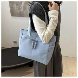 Detail of light blue nylon tote bag with side pocket and woven rope zipper pull