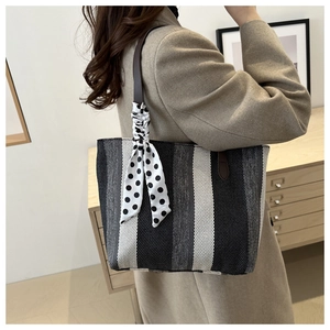 Detailaufnahme einer gestreiften Canvas-Tote-Bag mit gepunktetem Seidenschal am Griff