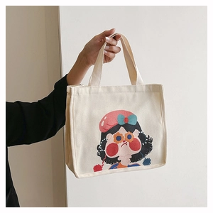 Close-up of canvas hand bag featuring a cute cartoon girl illustration and wide strap