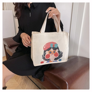Close-up of cream canvas tote bag featuring cute cartoon girl illustration and sturdy handles