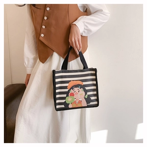 Detail of striped canvas tote bag featuring a cute cartoon girl illustration and black handle