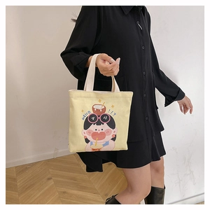 Dettaglio della borsa a secchiello in tela gialla con illustrazione di ragazza cartoon e manici