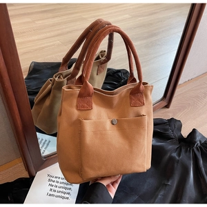 Detalle de bolso tote de lona marrón con bolsillo frontal con cierre magnético de metal