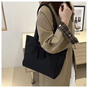 Dettaglio della borsa tote nera con tasche laterali e decorazioni in corda intrecciata