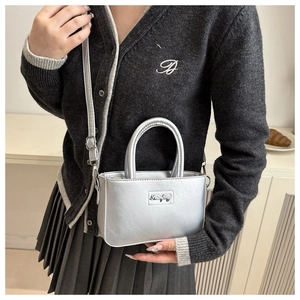 Detail of silver metallic mini square handbag with top handle and adjustable strap