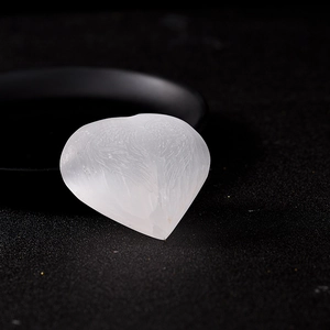 Hand-carved heart-shaped selenite crystal with wing patterns on a black tray