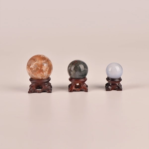 Three natural crystal spheres with ornate dark wood stands for home and office decor