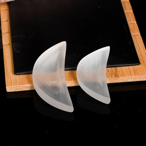 Pair of crescent-shaped translucent silicone breast pads on a minimalist wooden tray