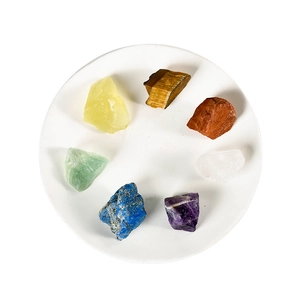 Seven natural irregular healing crystals set in a circular arrangement on white tray