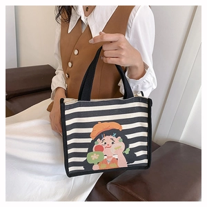 Detail of striped canvas tote bag featuring girl illustration and black strap handles