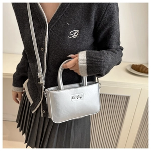 Close-up of a silver metallic mini bucket bag with adjustable strap and logo plate detail