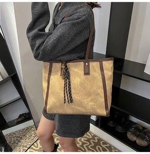 Detail einer khakifarbenen Segeltuch-Tasche mit braunen Ledergriffen und Fransenanhänger