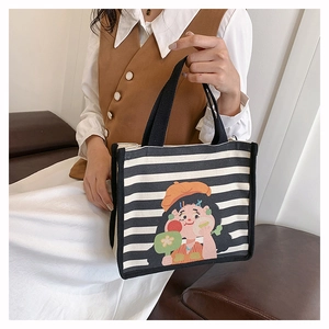 Detailed shot of striped canvas tote bag featuring a cute hand-painted cartoon girl