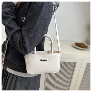 Close-up of creamy white crossbody bag with Shanfeng logo and adjustable shoulder strap