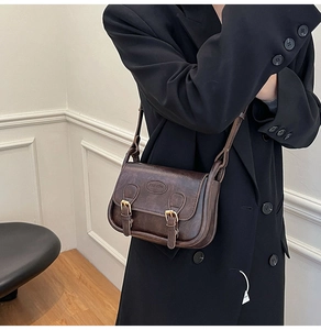 Detail of vintage brown crossbody bag with fashion embossed logo and metal buckle