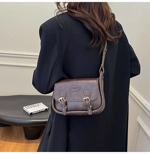 Detail of dark brown retro square bag with golden buckles and embossed fashion logo