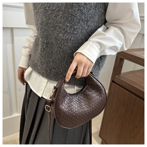 Detailed close-up of dark brown woven crescent handbag with premium PU leather texture