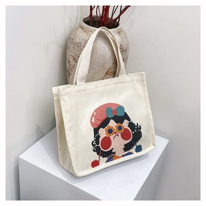 Detailed view of cream canvas tote bag with artistic cartoon girl illustration and sturdy handles