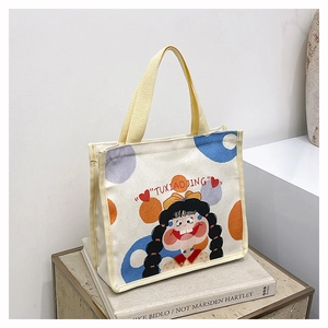 Detail of small canvas bag with yellow handles, cute girl print, and colorful polka dots