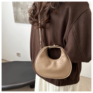 Detail of beige woven texture crossbody bag with hollow handle and adjustable strap