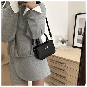Side view of a black mini crossbody bag worn by a model in a cozy indoor setting