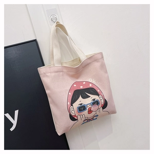 Dettaglio della borsa in tela rosa con stampa di ragazza cartoon e manici robusti