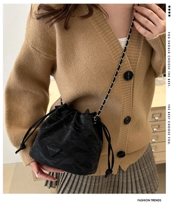 Detail of black nylon bucket bag with drawstring closure and chain strap on model