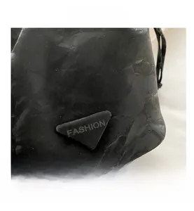 Macro view of black crinkle leather texture and triangle logo plate on bucket bag
