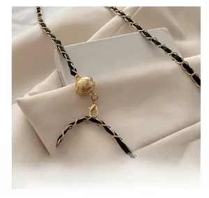 Close-up of golden chain strap with woven black leather and quilted metal ball detail