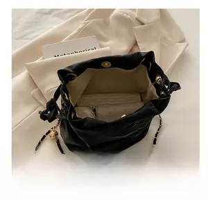 Internal storage view of black matte leather bucket bag with chain strap and essentials