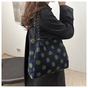 Detail of navy velvet polka dot tote bag with black woven handles on model shoulder