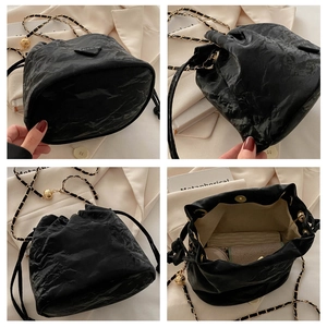 Detail view of the black pleated bucket bag showing the chain strap and spacious interior
