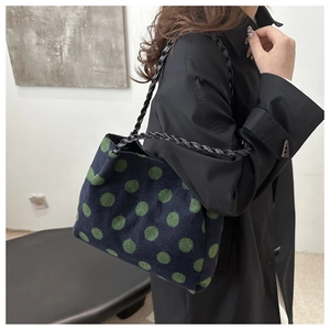 Detail of navy tote bag with green polka dots and black leather braided strap