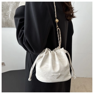 Detail of white marble-textured bucket bag with golden chain and adjustable ball