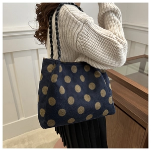Détail du grand sac cabas bleu marine à pois dorés porté par un mannequin de mode