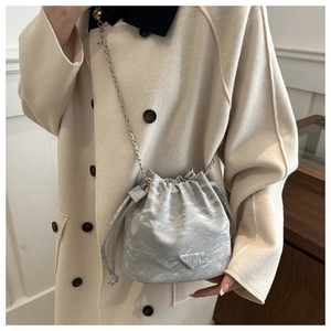 Detail view of silver-grey drawstring bucket bag with chain strap and metal logo