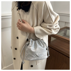 Close-up of a silver drawstring bucket bag with marble texture and metal chain strap