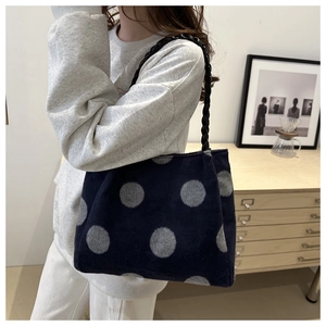 Detail view of navy blue polka dot plush tote bag with a woven chain shoulder strap