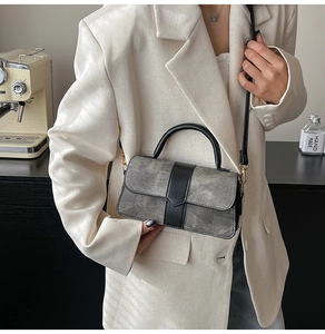 Detalle de un bolso gris vintage con ribete negro y accesorios metálicos dorados