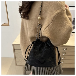Detail of black drawstring bucket bag with golden chain and fashion logo on soft leather