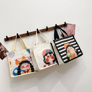 Three cute canvas tote bags with girl illustrations hanging on a wooden wall hook