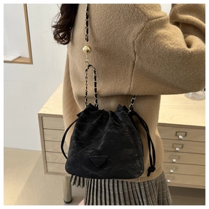 Detail of black drawstring bucket bag featuring a fashion logo and adjustable chain strap