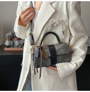 Detail of grey textured flap handbag with tennis racket charm and black leather handle