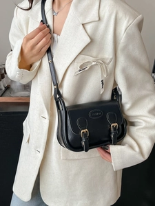 Classic black PU leather mini messenger bag with gold hardware worn on white blazer