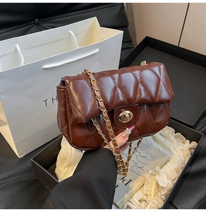 Detailed shot of dark brown quilted leather bag with gold chain and twist lock on a desk