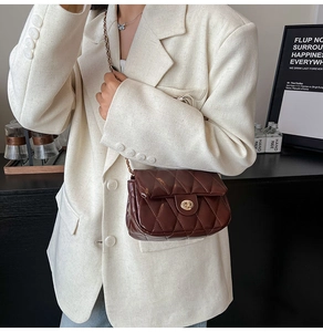 Detail of dark brown quilted crossbody bag with gold chain and metal twist lock closure