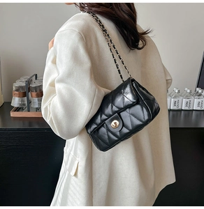 Close-up of black quilted leather shoulder bag with gold chain strap and turn-lock